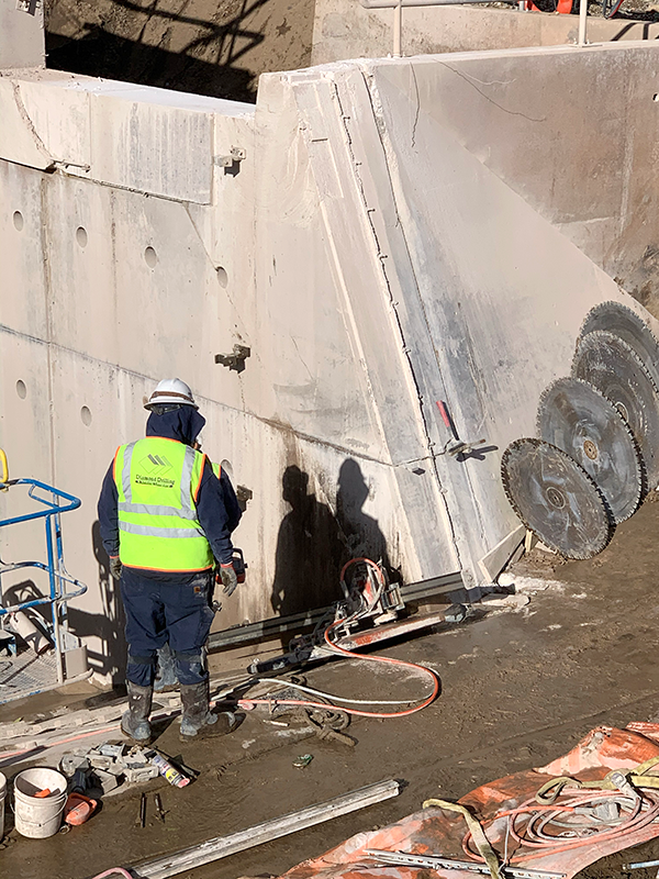 A Reclamation contractor in a yellow vest sets up a diamond saw at the Durango Pumping Plant intake structure to cut a section of the gray concrete so it can be removed.