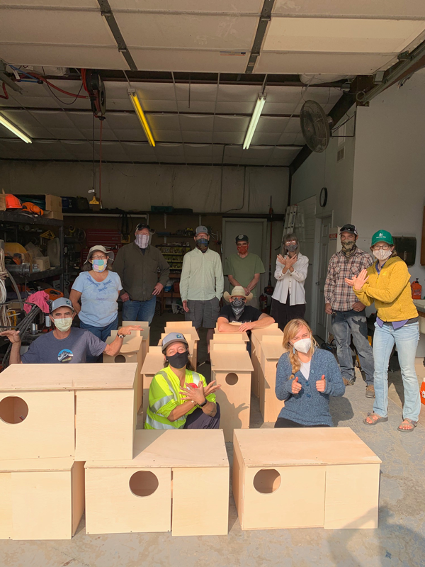 10 volunteers pose with the completed bird boxes inside the warehouse at Grand Junction Wildlife Area.  Photo by Melissa Werkmeister 