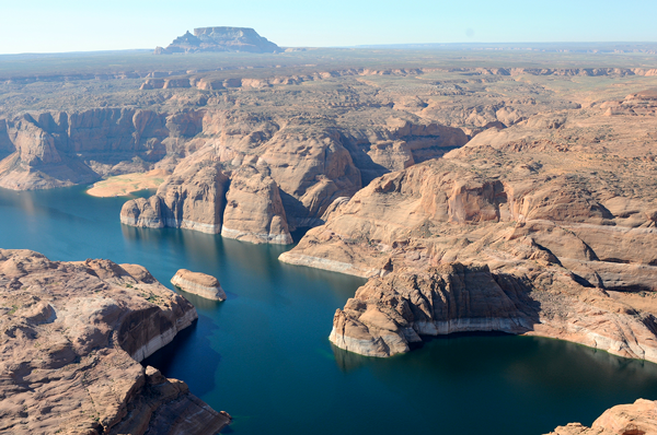 Aerial view of the Colorado River flowing through red rock canyons with a visible white bathtub ring due to low water levels. 