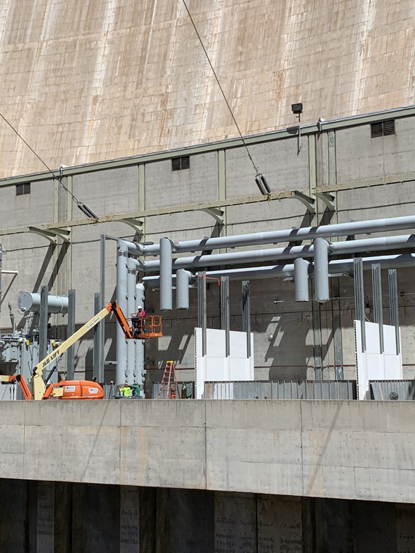 Workers installing the bus and barriers around the K7A transformer bank with the help of a lift.