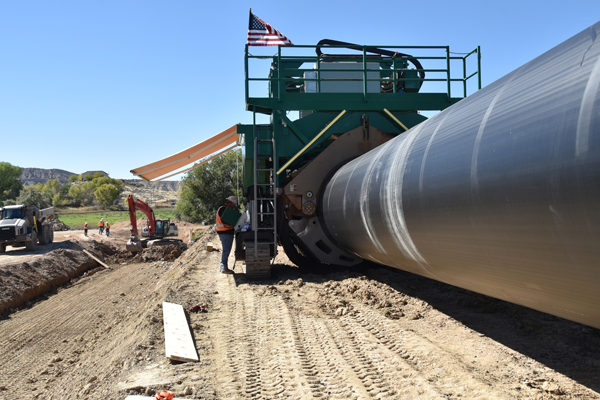 Workers at the Steinaker Service Canal Pipeline Project site operate a Talon fusing machine to fuse together two sections of 84-inch-diameter HDPE pipe.