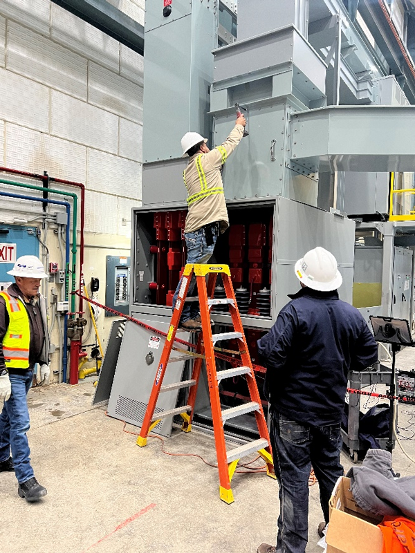 Contracted employees finish up installing the new breakers in their cabinet.