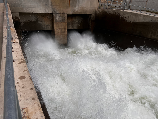 Large concrete square outlet works with two large streams of fast, splashing, white water