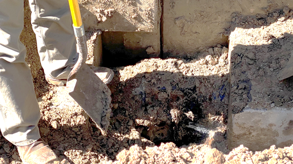 Bottom of an exploratory pothole showing the leaking joint spraying water.